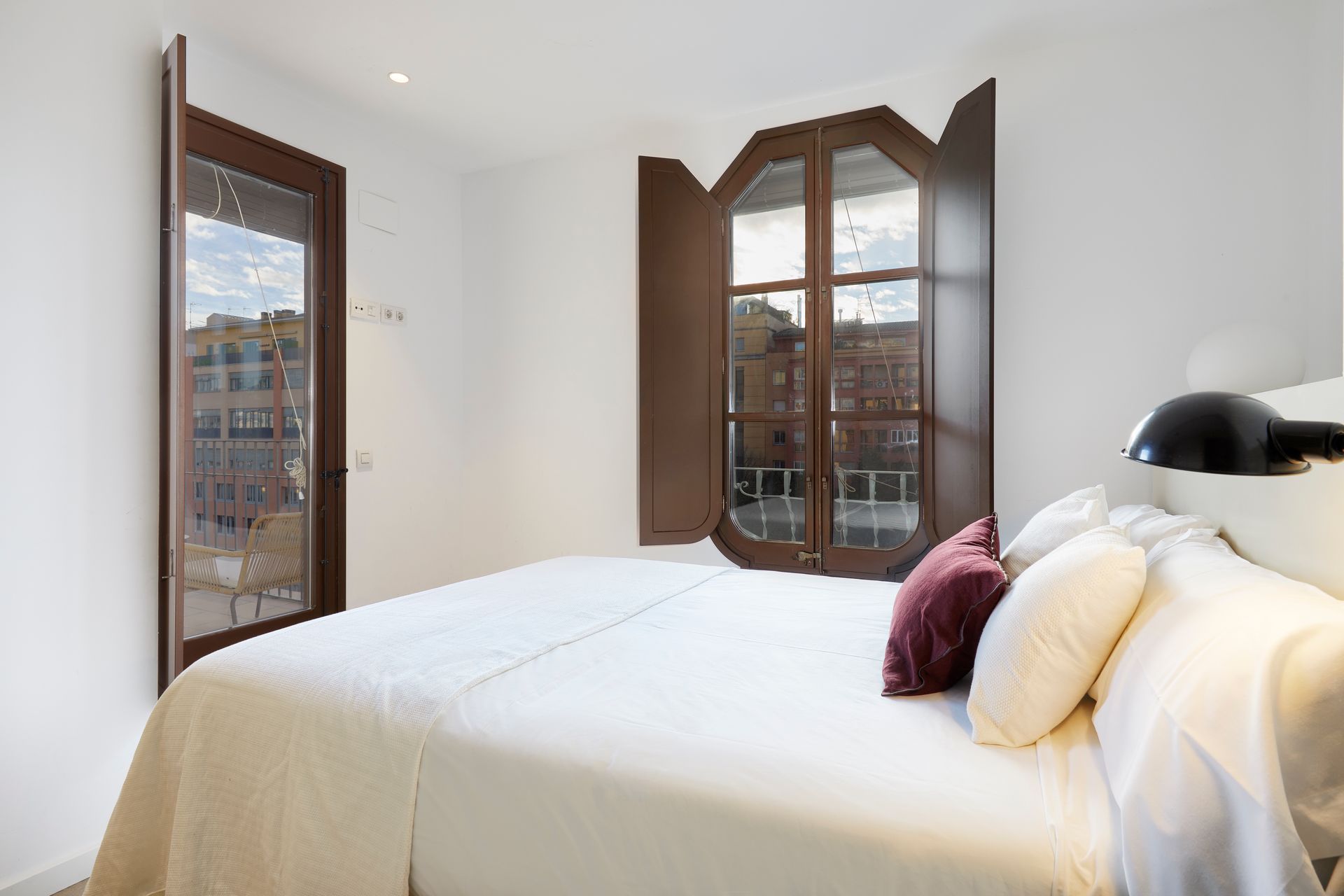 A bedroom with a bed and a window with shutters.