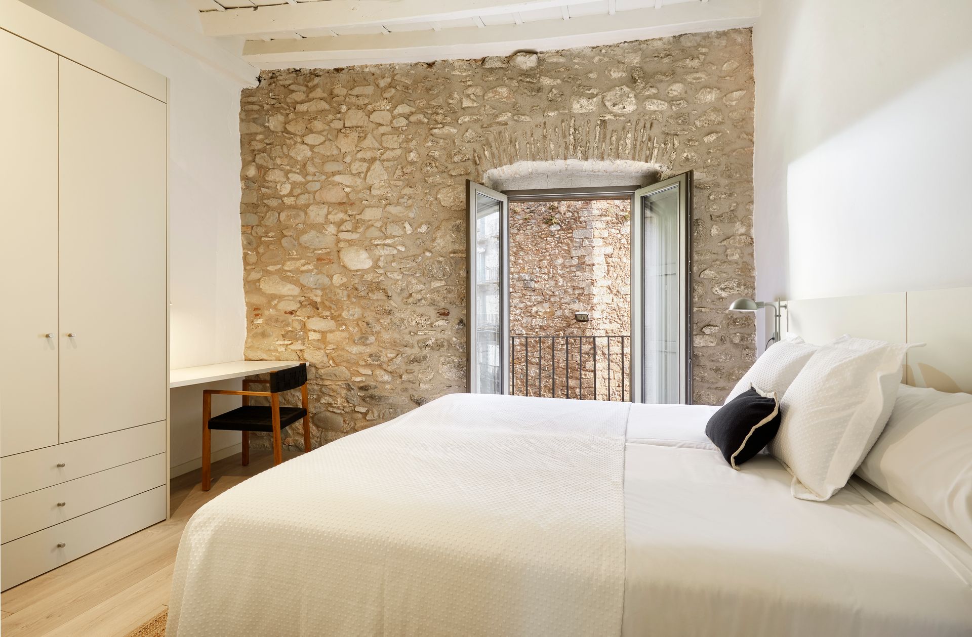 A bedroom with a large bed and a stone wall.