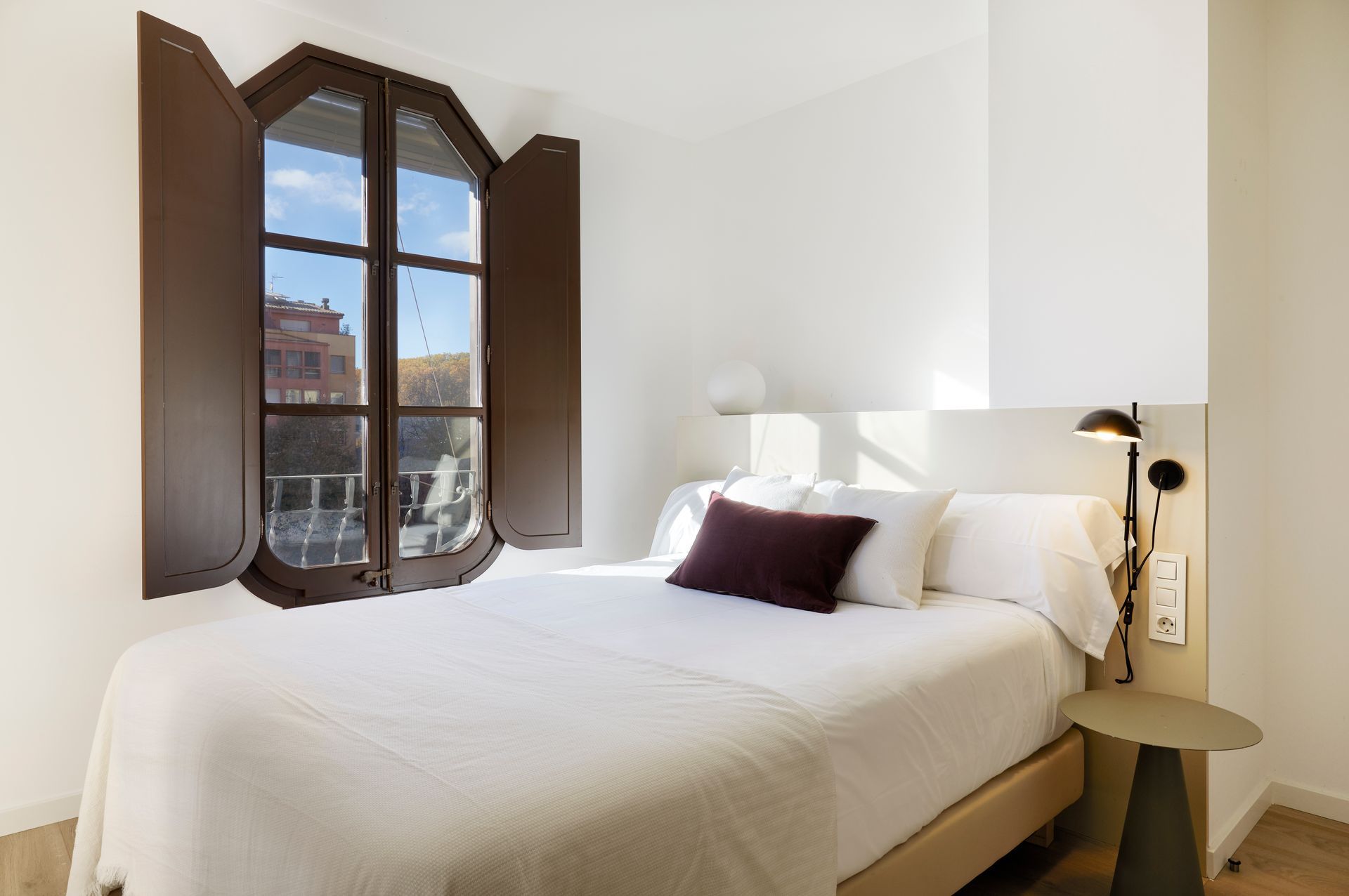 A bedroom with a bed and a window with shutters.