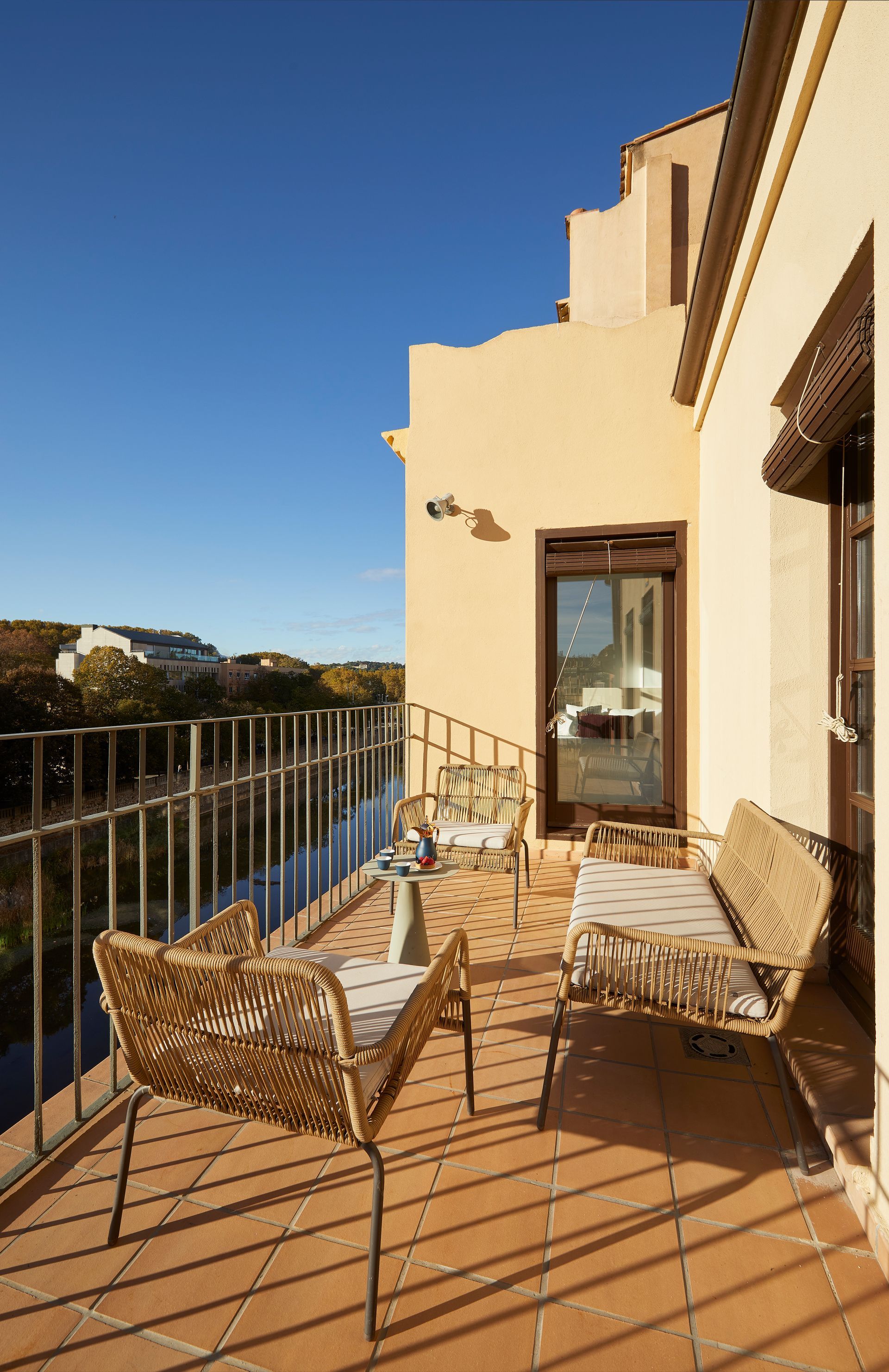 A balcony with wicker furniture and a view of a river.