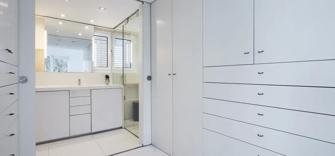 A bathroom with white cabinets , a sink and a mirror.