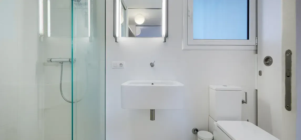A bathroom with a toilet , sink and shower.