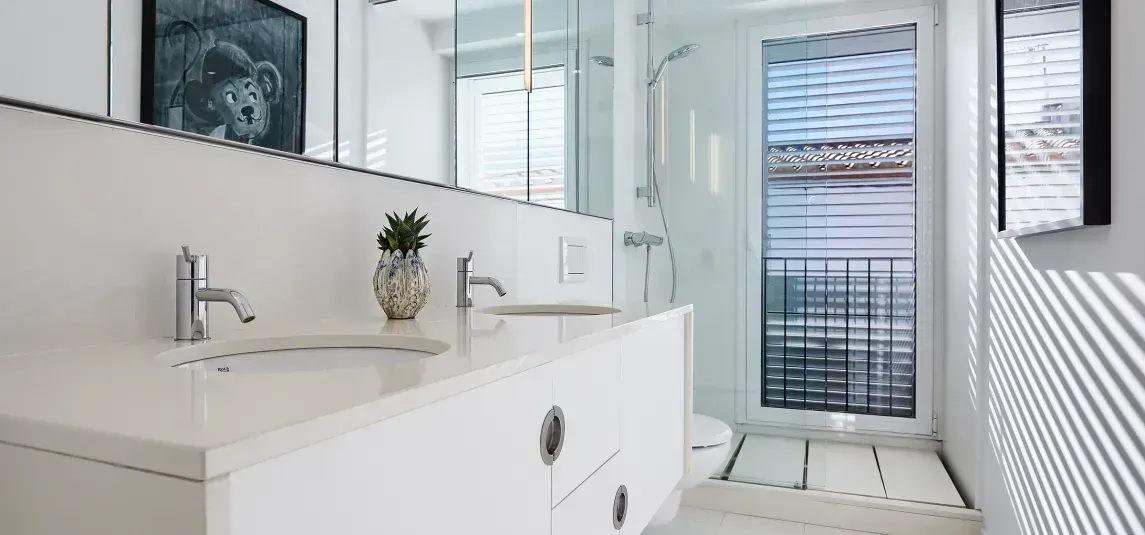 A bathroom with a sink , toilet , shower and mirror.