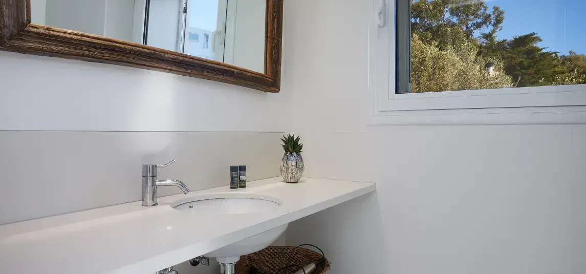 A bathroom with a sink , mirror and window.