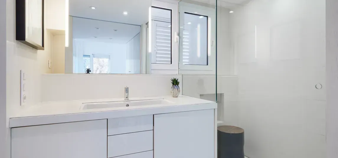 A bathroom with a sink , mirror and walk in shower.