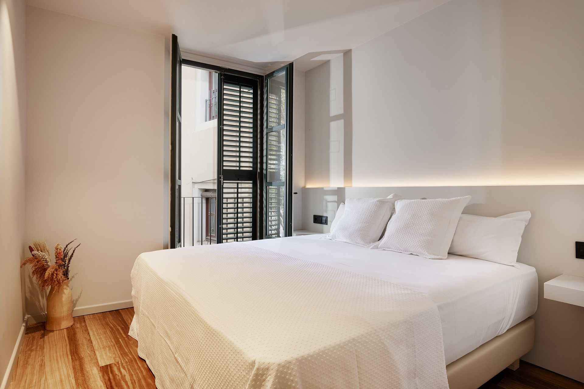 A bedroom with a large bed and a balcony.