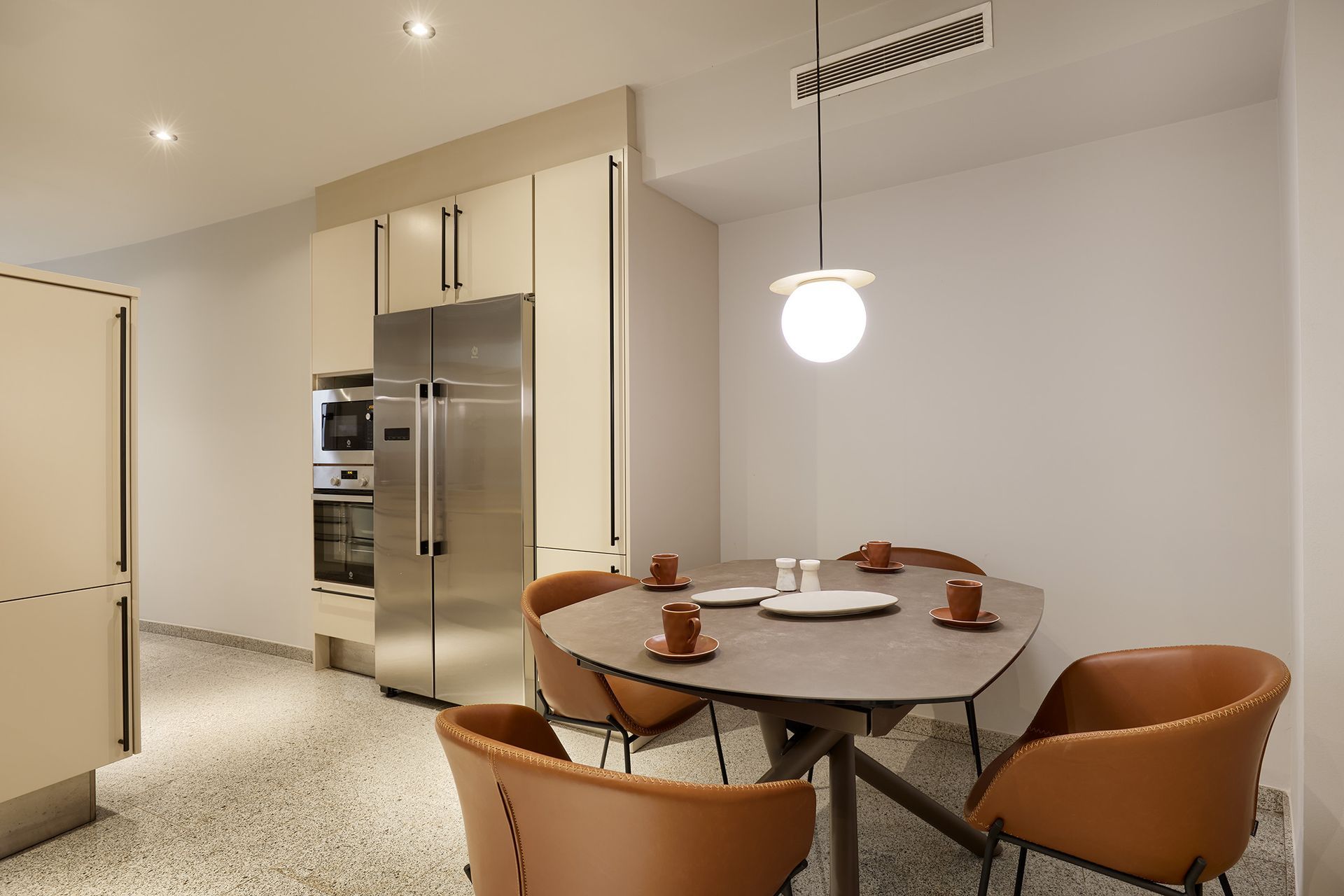 A dining room with a table and chairs and a refrigerator.