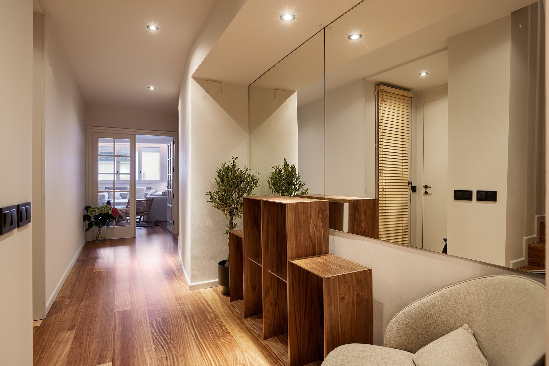 A hallway with hardwood floors and a large mirror