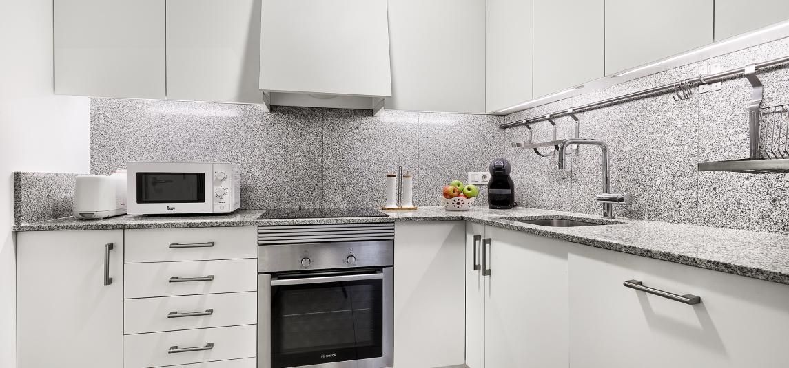 A kitchen with white cabinets , granite counter tops , stainless steel appliances and a microwave.