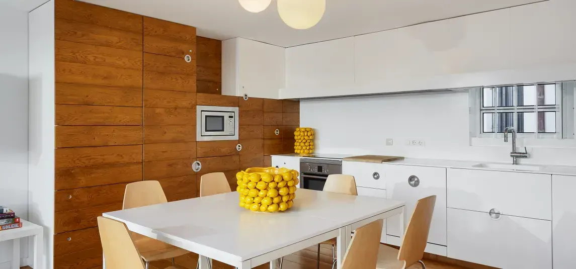 A kitchen with a table and chairs and a bowl of lemons on the table.