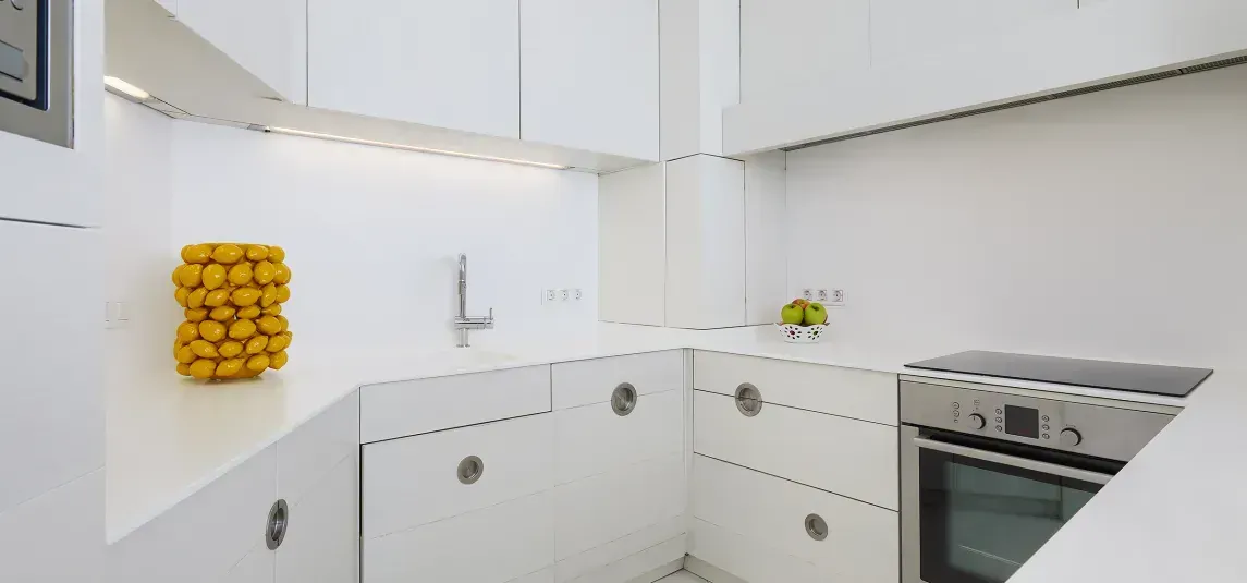 A kitchen with white cabinets and a stove top oven