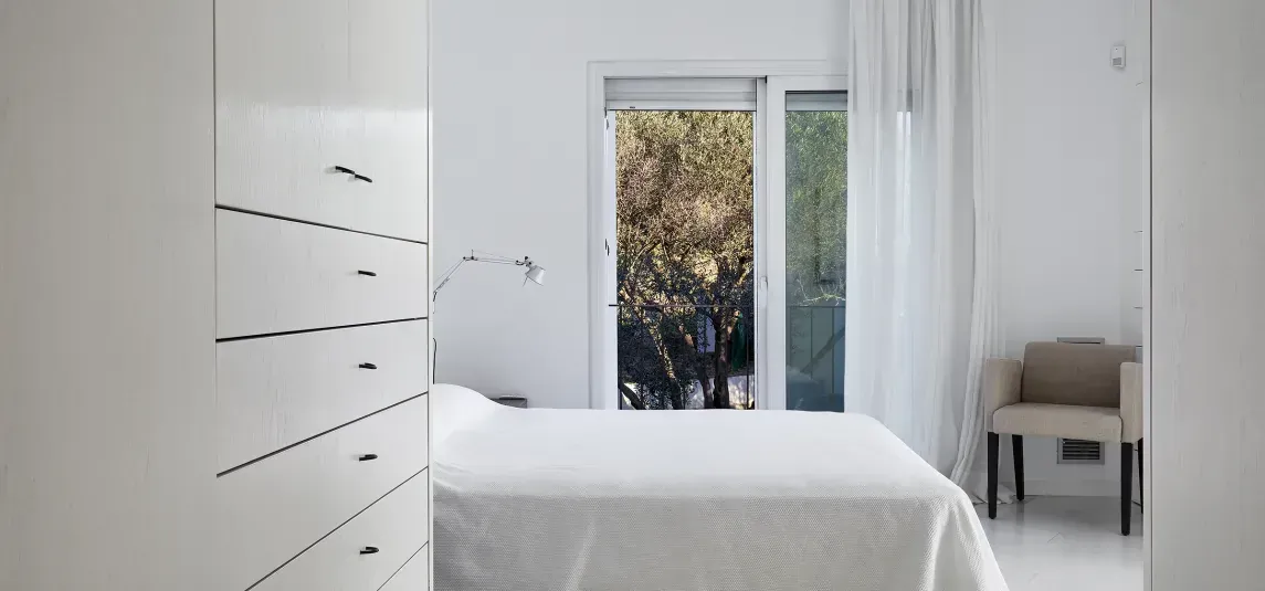 A bedroom with a bed , chair , dresser and window.