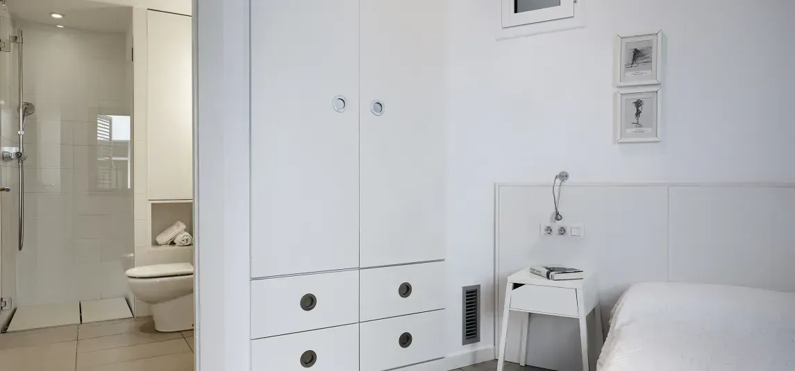 A bedroom with a bed , nightstand , cabinets and a bathroom.