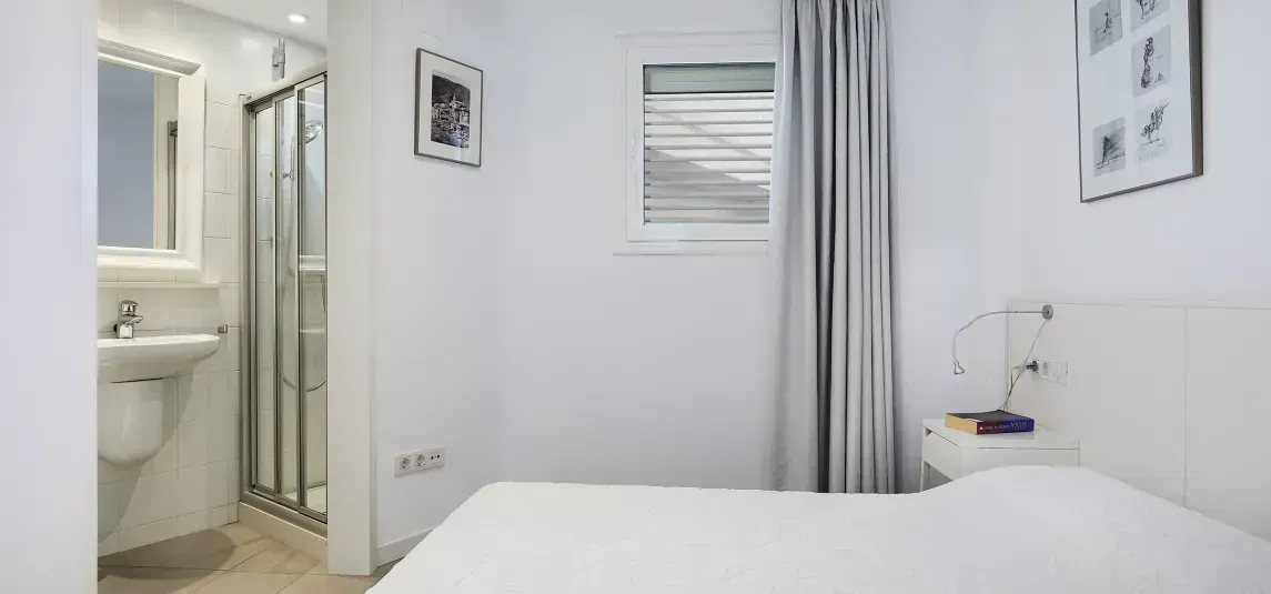 A bedroom with a bed , sink , and shower.