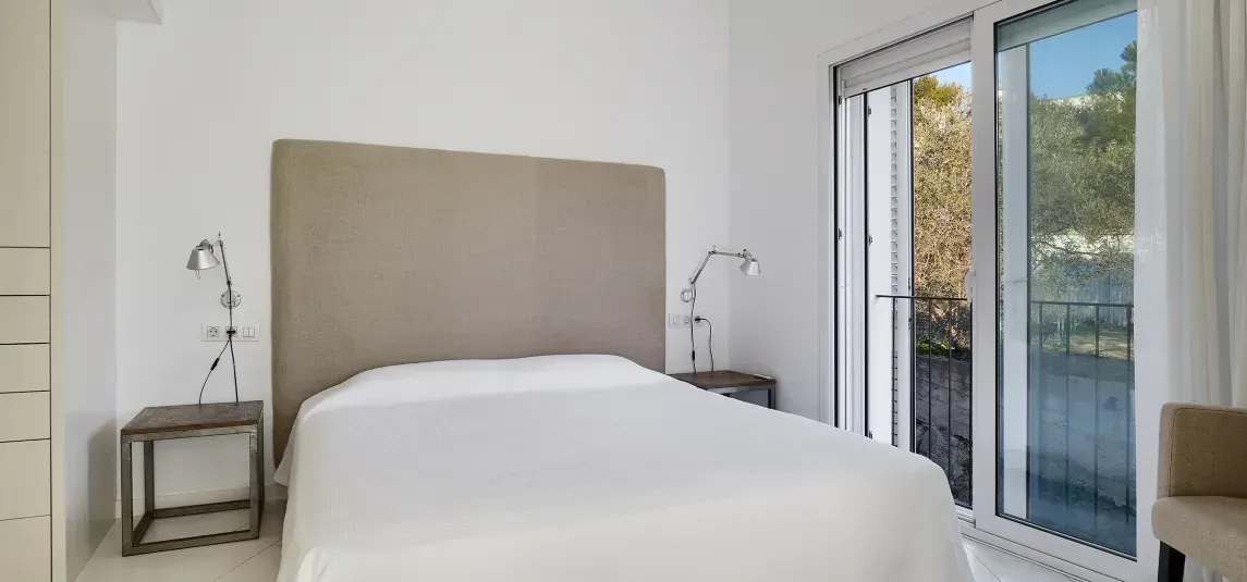 A bedroom with a bed , nightstands , and a sliding glass door.