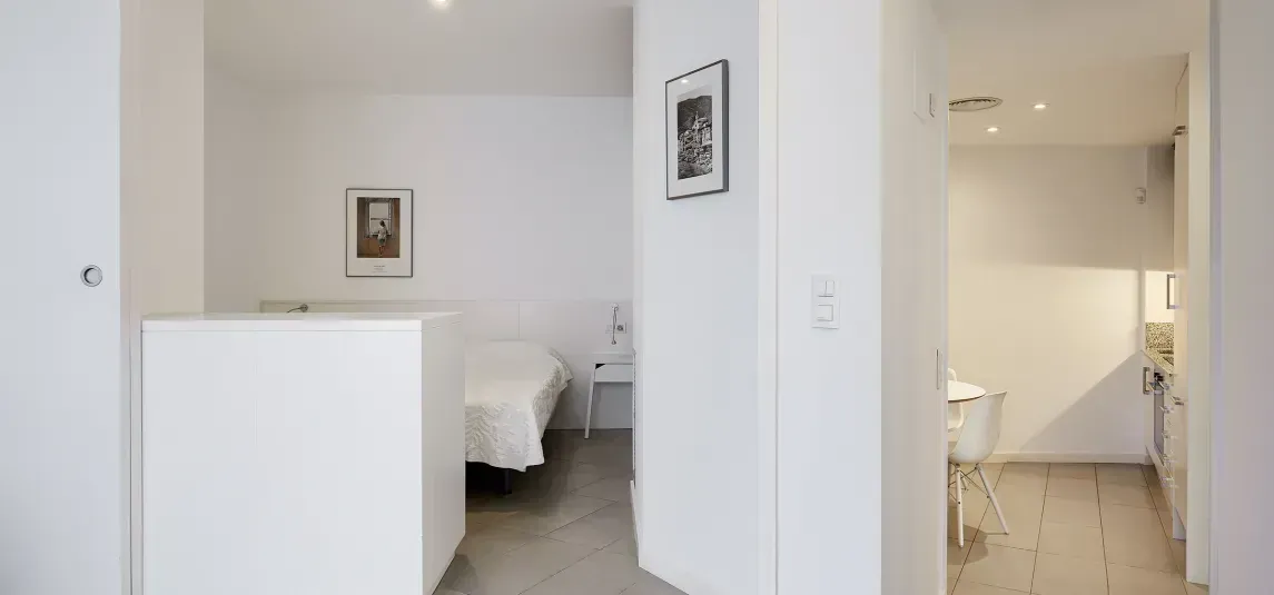 A hallway leading to a bedroom with a bed and a bathroom.