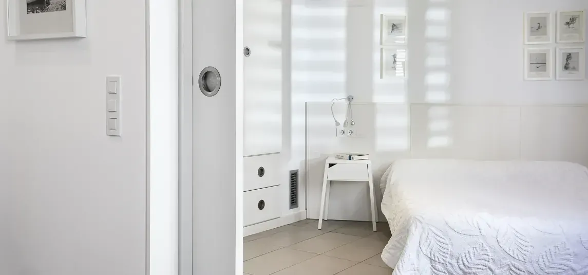 A bedroom with a bed , nightstand , and mirror.