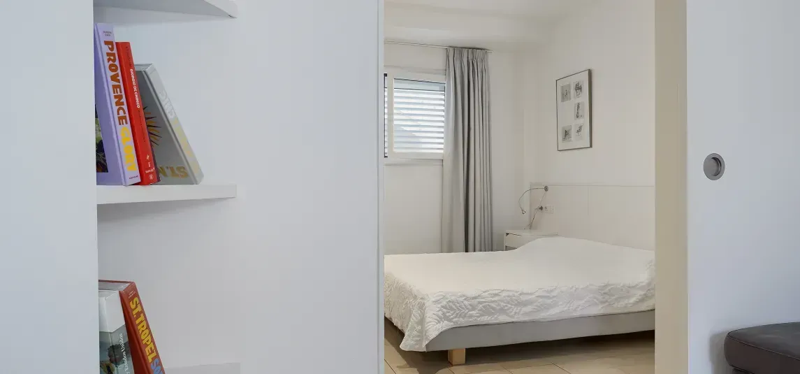 A bedroom with a bed and a bookshelf with books on it.