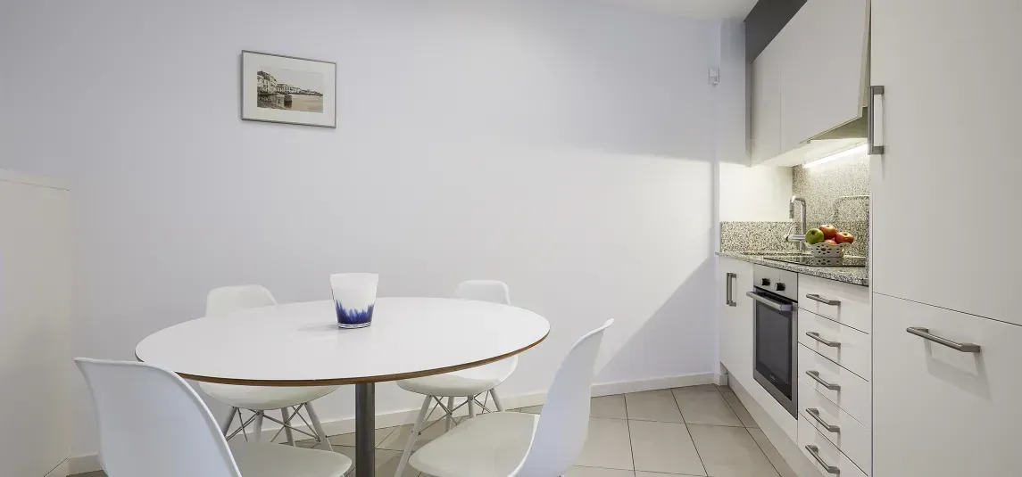 A kitchen with a table and chairs and a picture on the wall.
