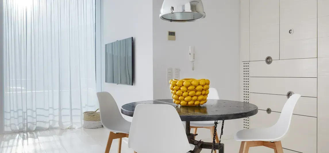 A dining room with a table and chairs and a bowl of lemons.