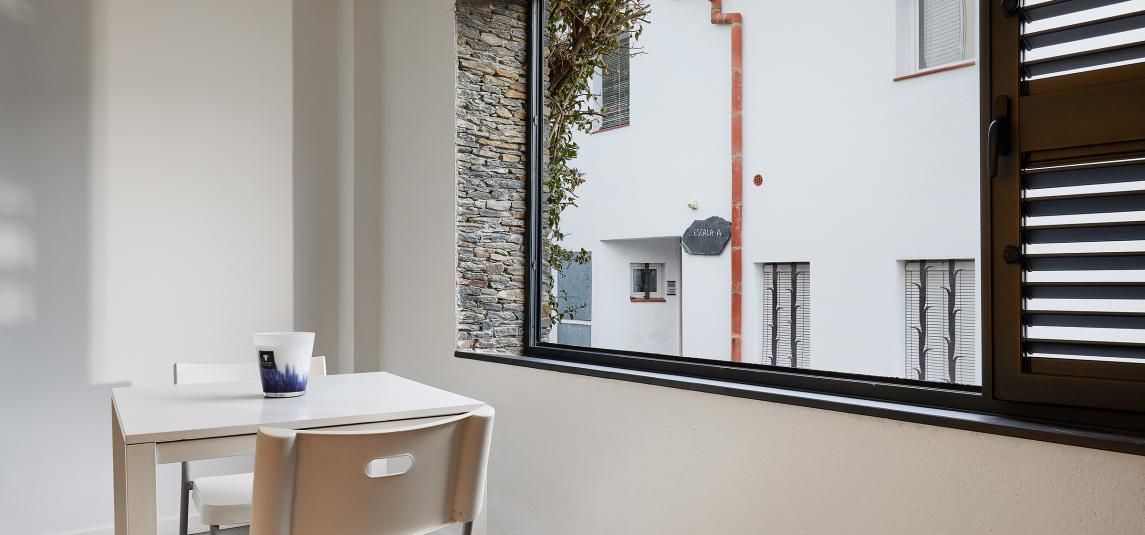 There is a table and chairs in front of a window with shutters.