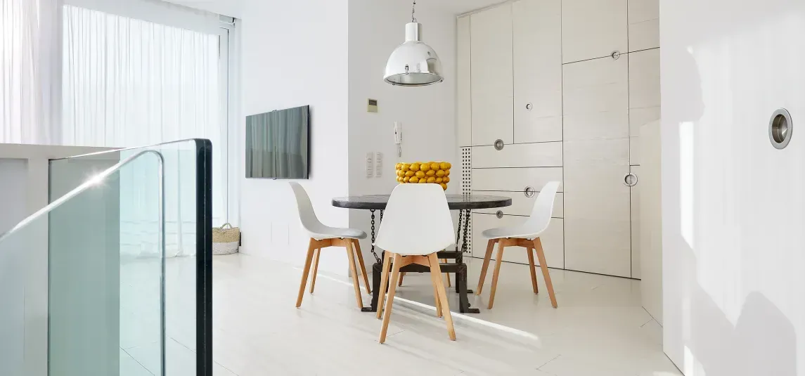 A dining room with a table and chairs in a white room.