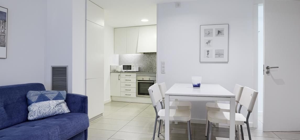 A living room with a blue couch and a white table and chairs