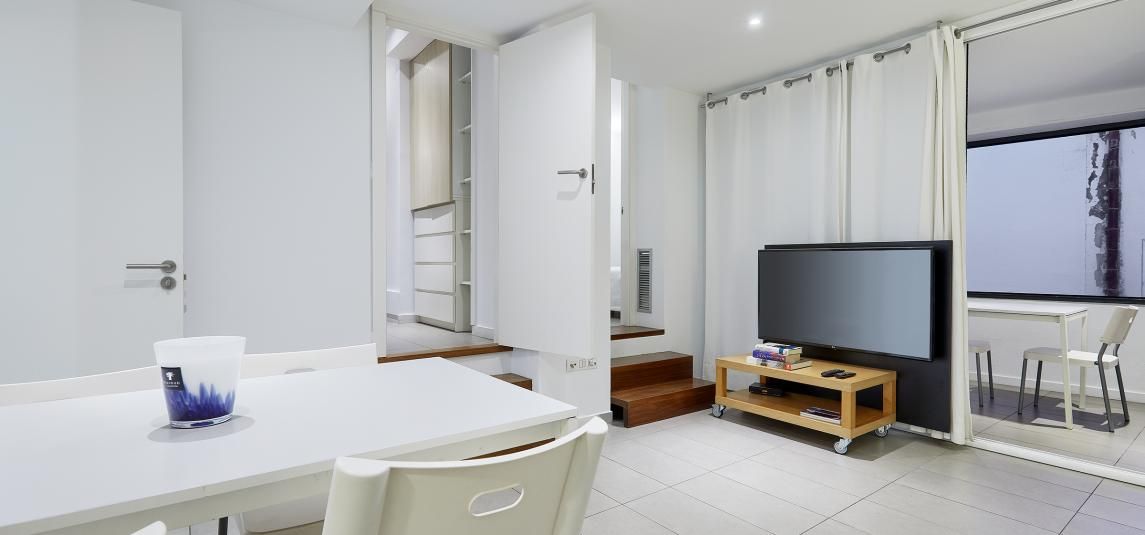 A living room with a table and chairs and a television.