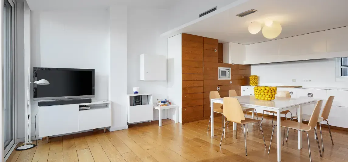 A living room with a dining table and chairs and a flat screen tv.