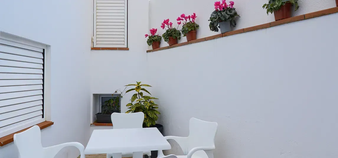 A patio with a table and chairs and potted plants on the wall