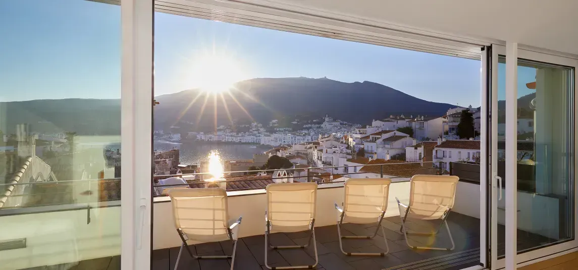 A view of a city from a balcony with a table and chairs.