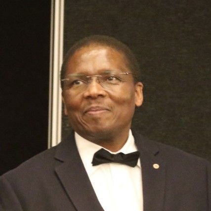 A man in a white shirt and red tie is smiling for the camera.