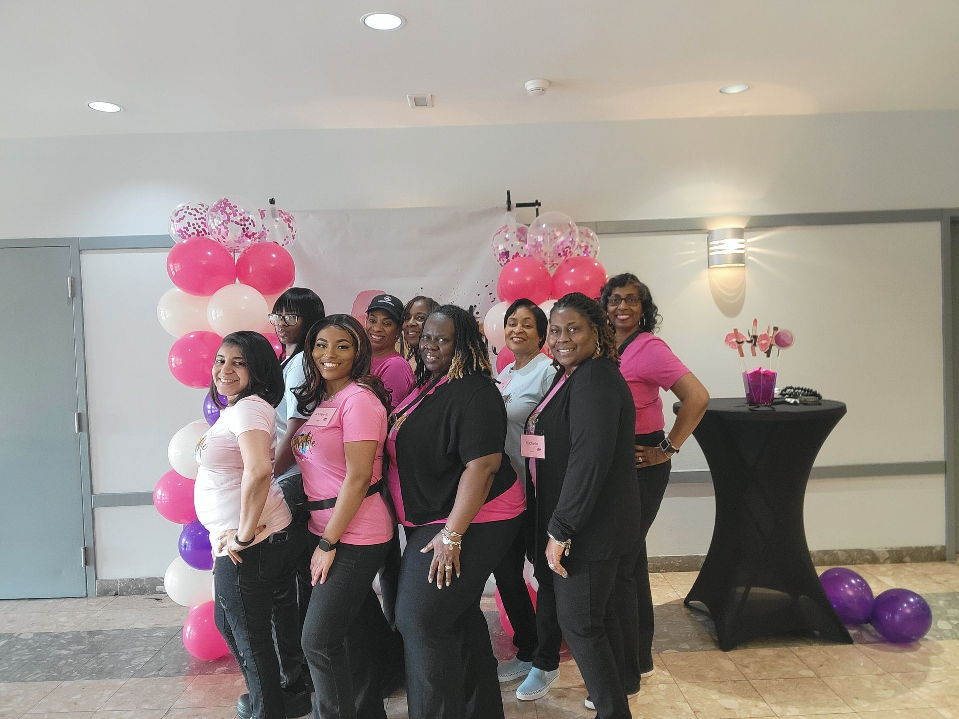 A group of women are posing for a picture in front of balloons.