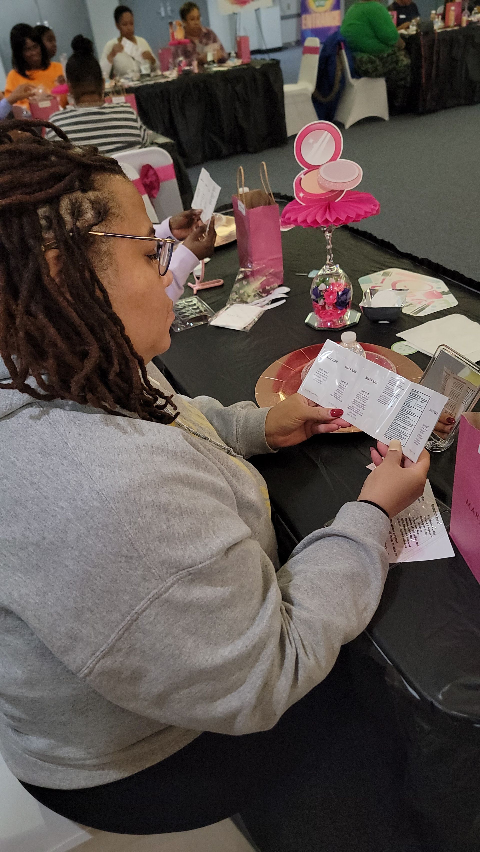 A woman is sitting at a table holding a piece of paper.
