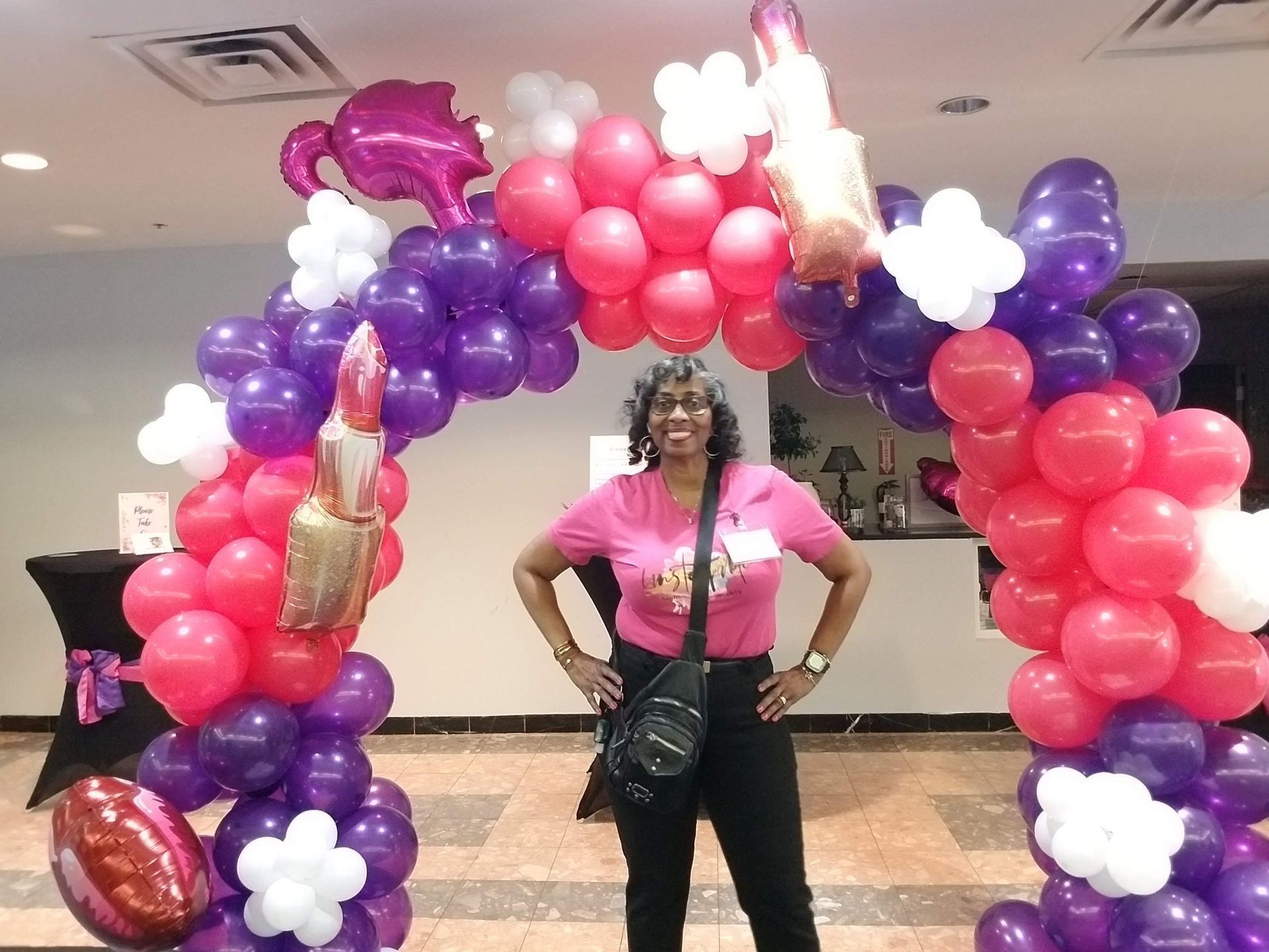 A woman is standing in front of a balloon arch.