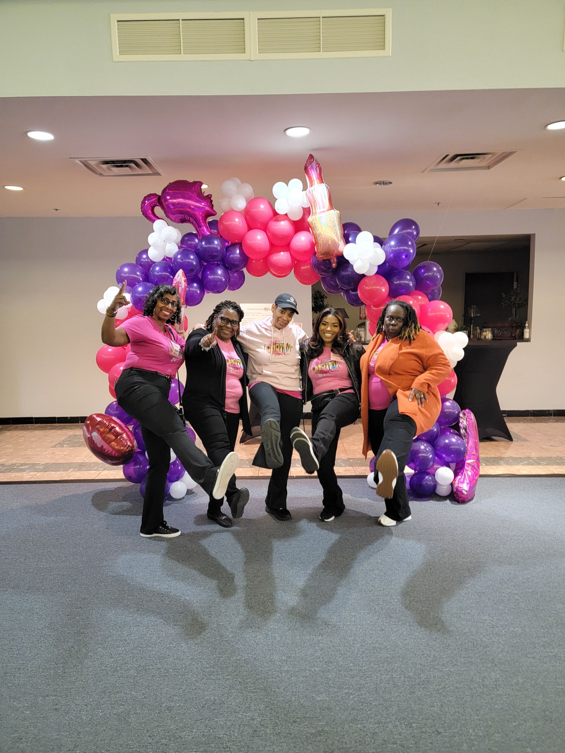 A group of people are posing for a picture in front of a balloon arch.