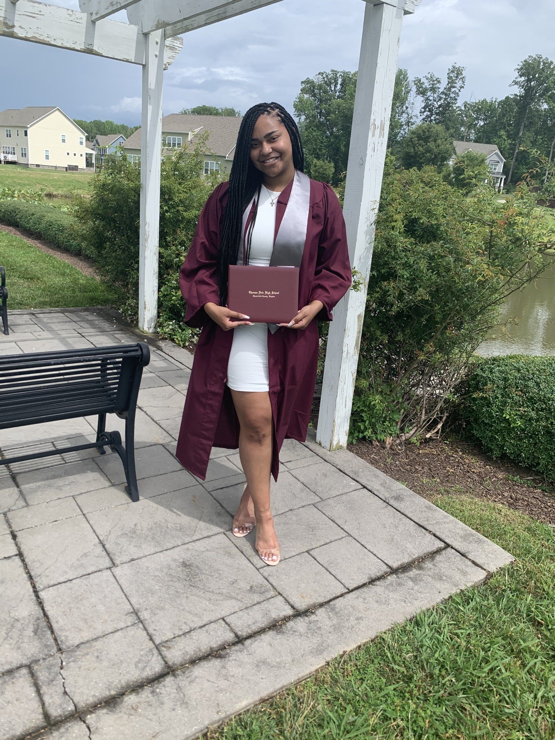 A woman in a graduation cap and gown is holding a diploma.