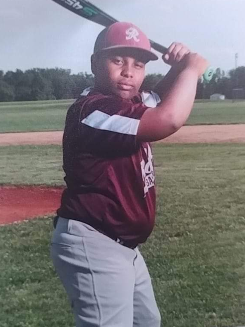 A young boy is holding a baseball bat on a field