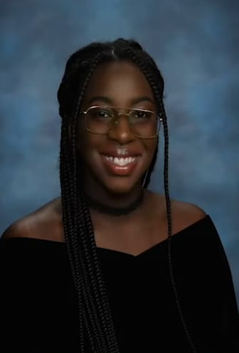 A woman wearing glasses and braids is smiling for the camera.