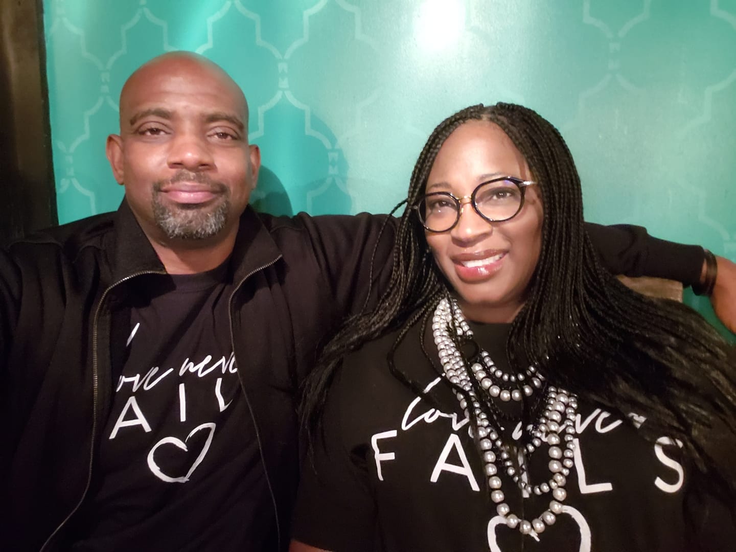 A man and a woman are posing for a picture and the woman is wearing a shirt that says 