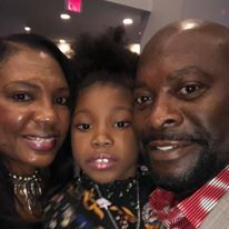 A man and a woman are posing for a picture with their daughter.