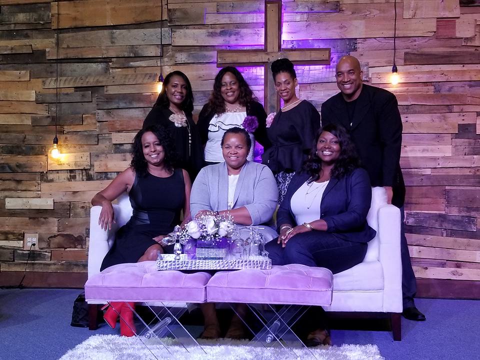 A group of people are posing for a picture while sitting on a couch.