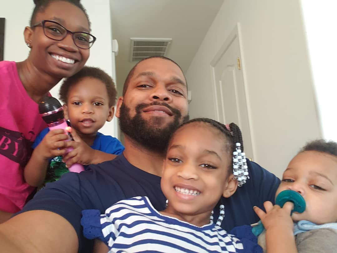 A man and woman are posing for a picture with their three children.