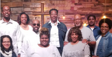 A group of people are posing for a picture in front of a wooden wall.