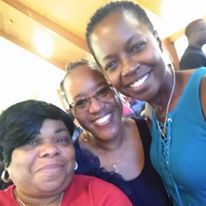 Three women are posing for a picture together and smiling for the camera.