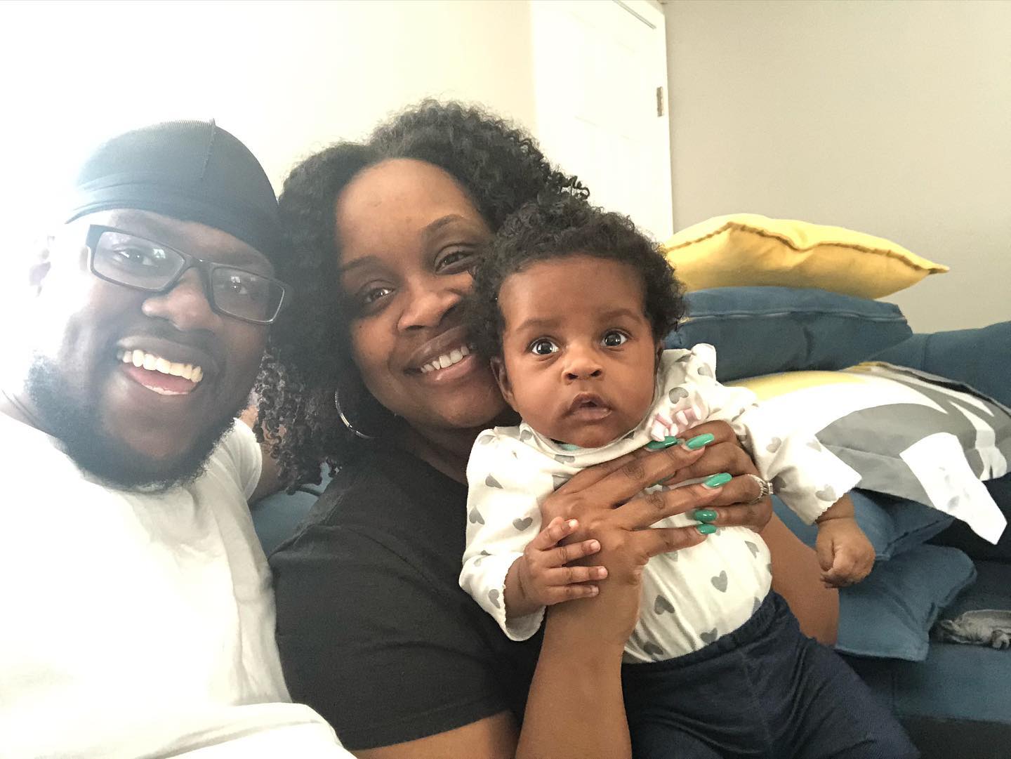 A man and woman are sitting on a couch holding a baby.
