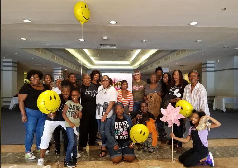 A group of people are posing for a picture with balloons and smiley faces.