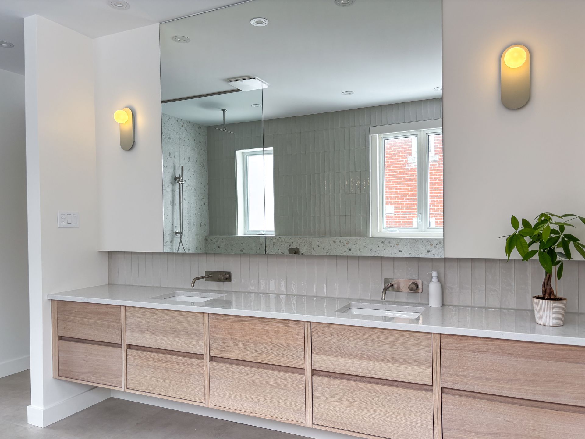 Salle de bain moderne avec grand miroir, vanité flottante en bois et deux appliques murales.