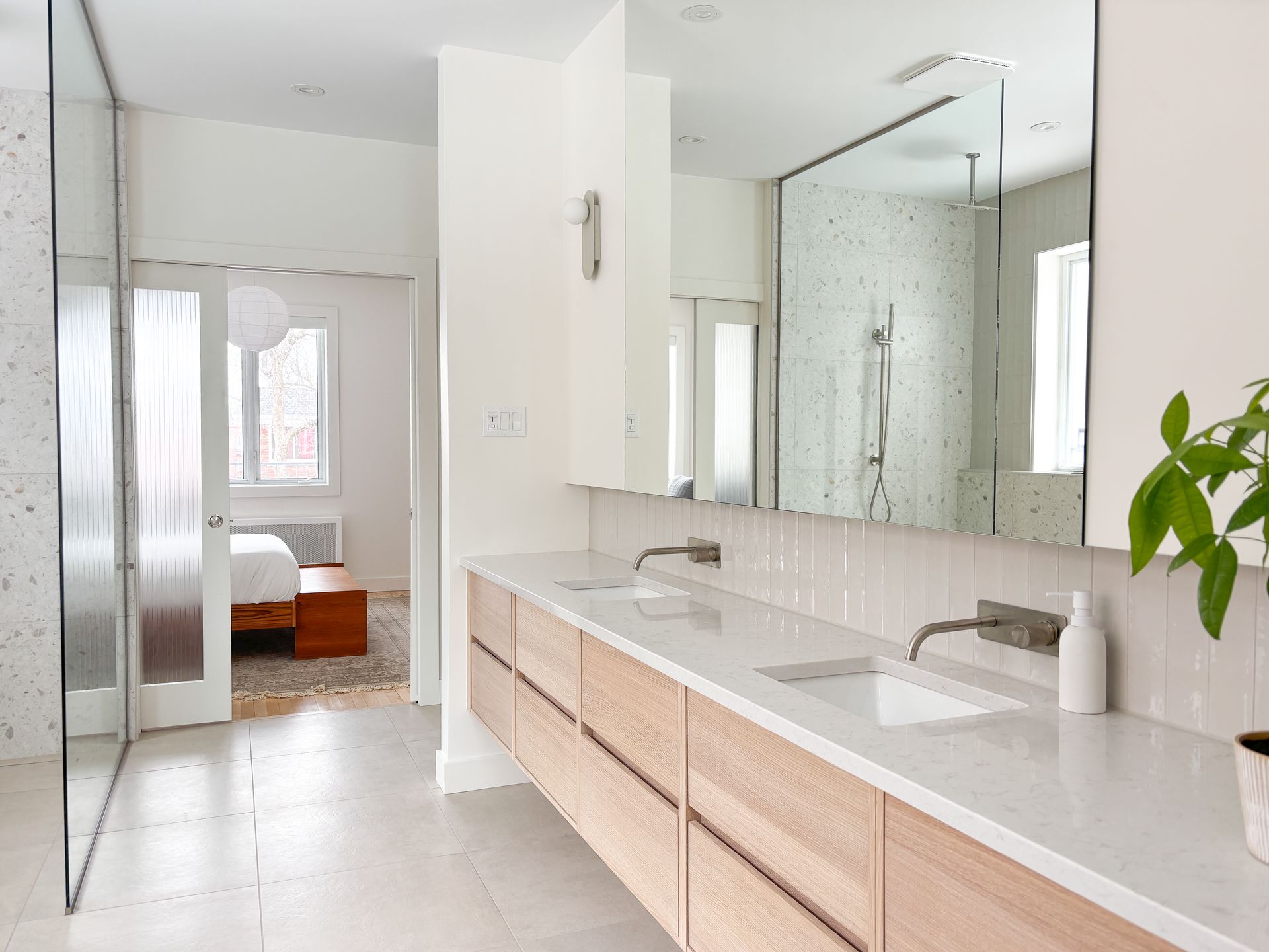 Salle de bain blanche moderne avec une longue vanité en bois, deux lavabos et un grand miroir.