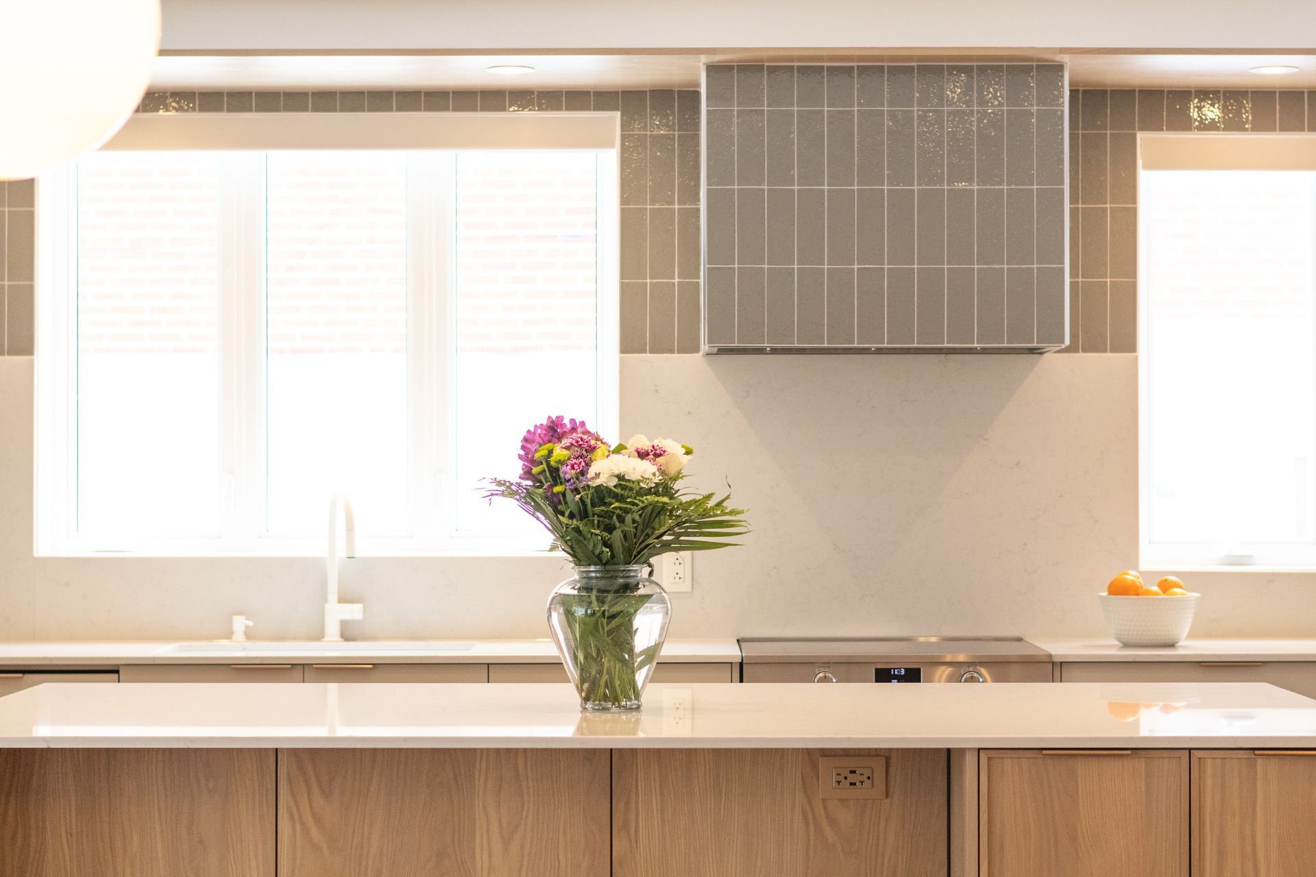 Cuisine moderne avec armoires en bois clair, comptoir et composition florale.